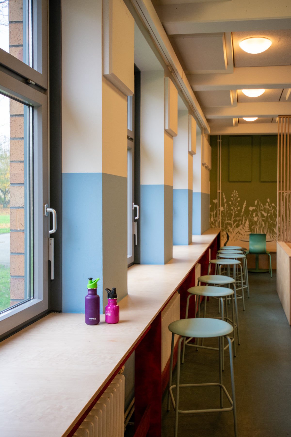 Gestaltung Schulmensa: Stehtisch mit Barhockern entlang der Fensterfront in der Clara-Grunwald-Schule Hamburg