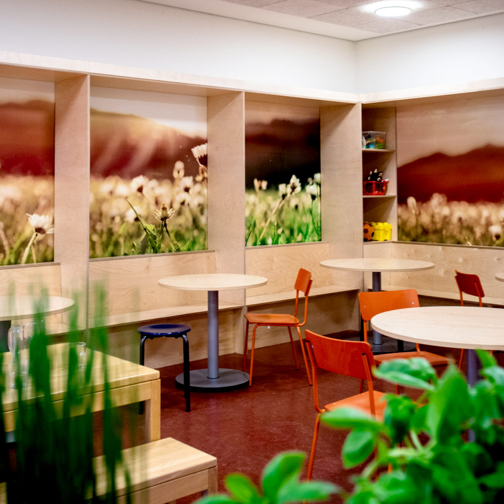 Sitznischen aus Holz mit runden Tischen und farbigen Stühlen in der Mensa der Grundschule Nettelnburg nach dem Entwurf von Junistudio aus Hamburg