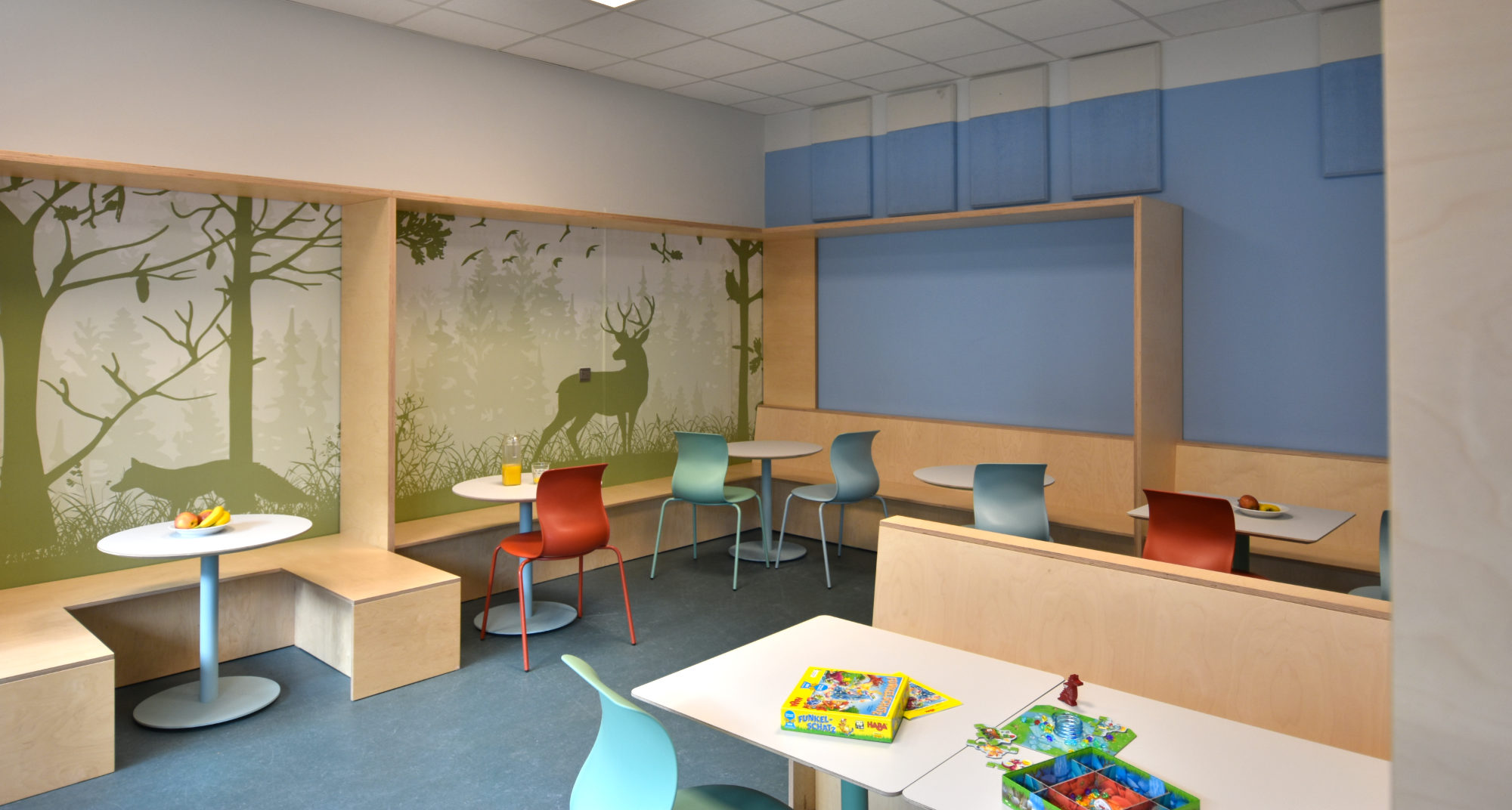 Speiseraum der Clara-Grunwald-Schule mit Wandgestaltung in Form einer Tapete mit stilisiertem Waldmotiv als raumprägendes Gestaltungselement.