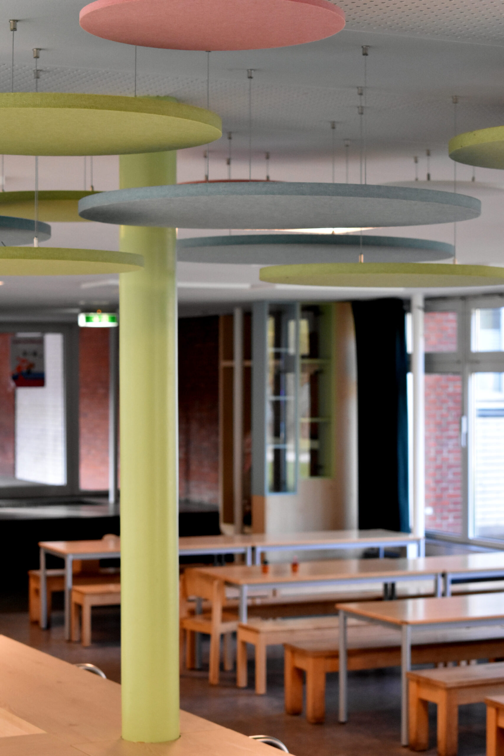 Runde Akustikpaneele an einer Säule gestaltet als stilisierter Baum in einer Grundschul-Mensa