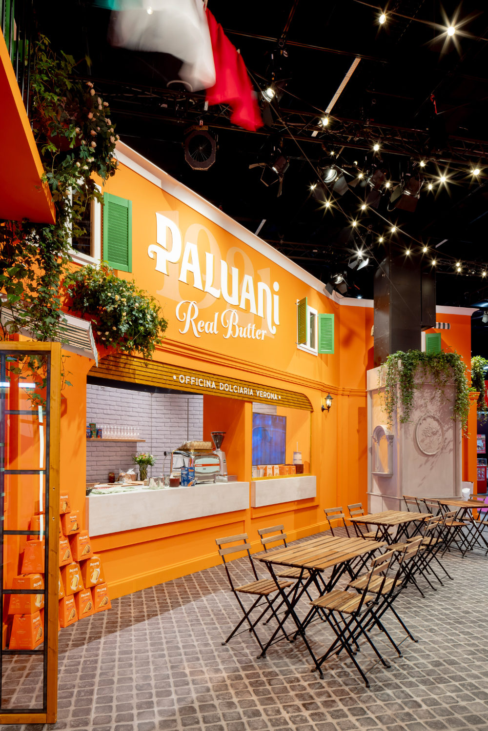 Caféartiger Sitzbereich im von Juni Studio entworfenen Paluani Messestand auf der ISM Köln mit Bistrotischen und Piazza-Atmosphäre