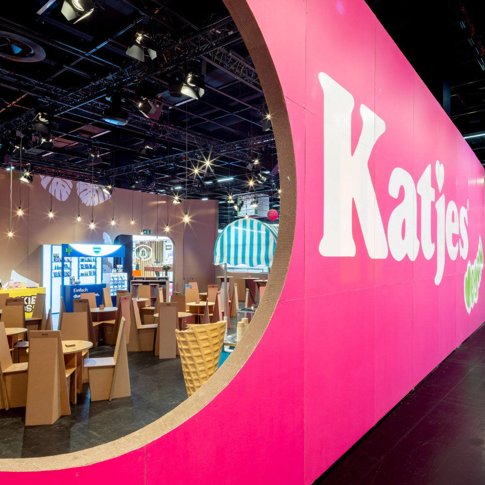 Pinkfarbener Katjes-Messestand aus Pappe auf der ISM 2026 mit großem runden Fensterausschnitt