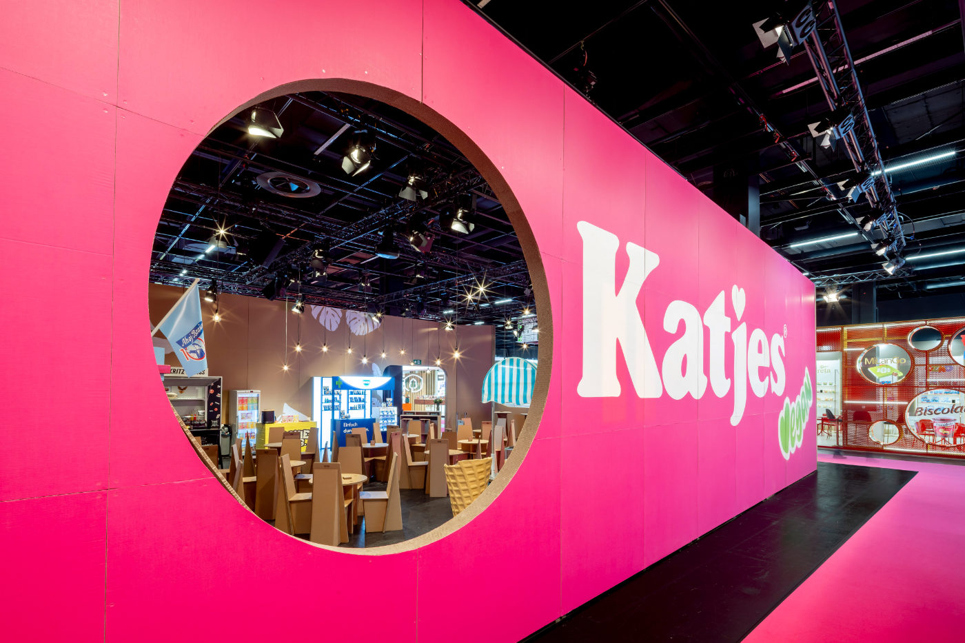 Pinkfarbene Fassade des Katjes-Messestands aus Pappe mit großem runden Ausschnitt und Blick in den Innenbereich